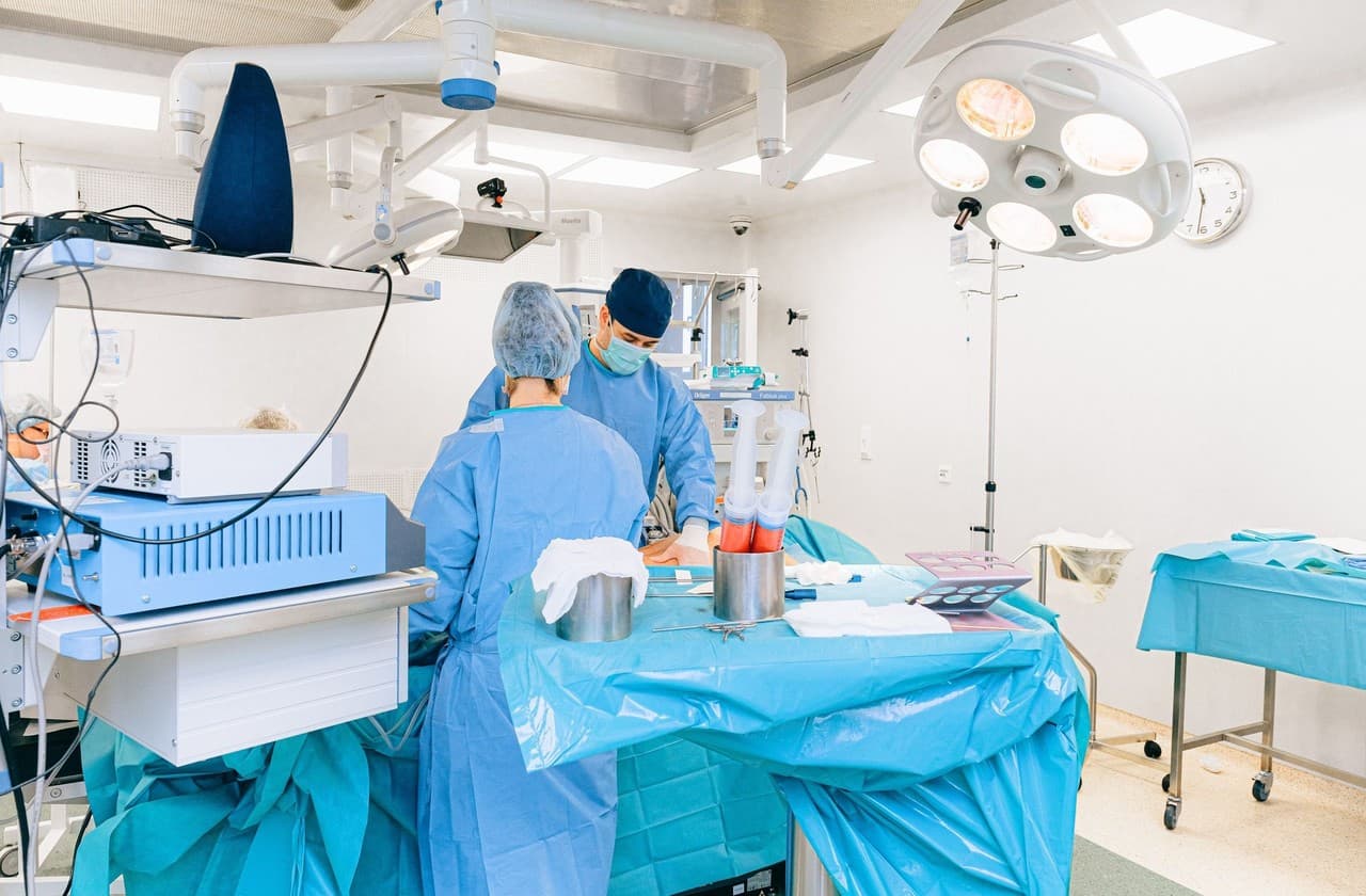 Surgical team in blue gowns at the operating table under a surgical lamp