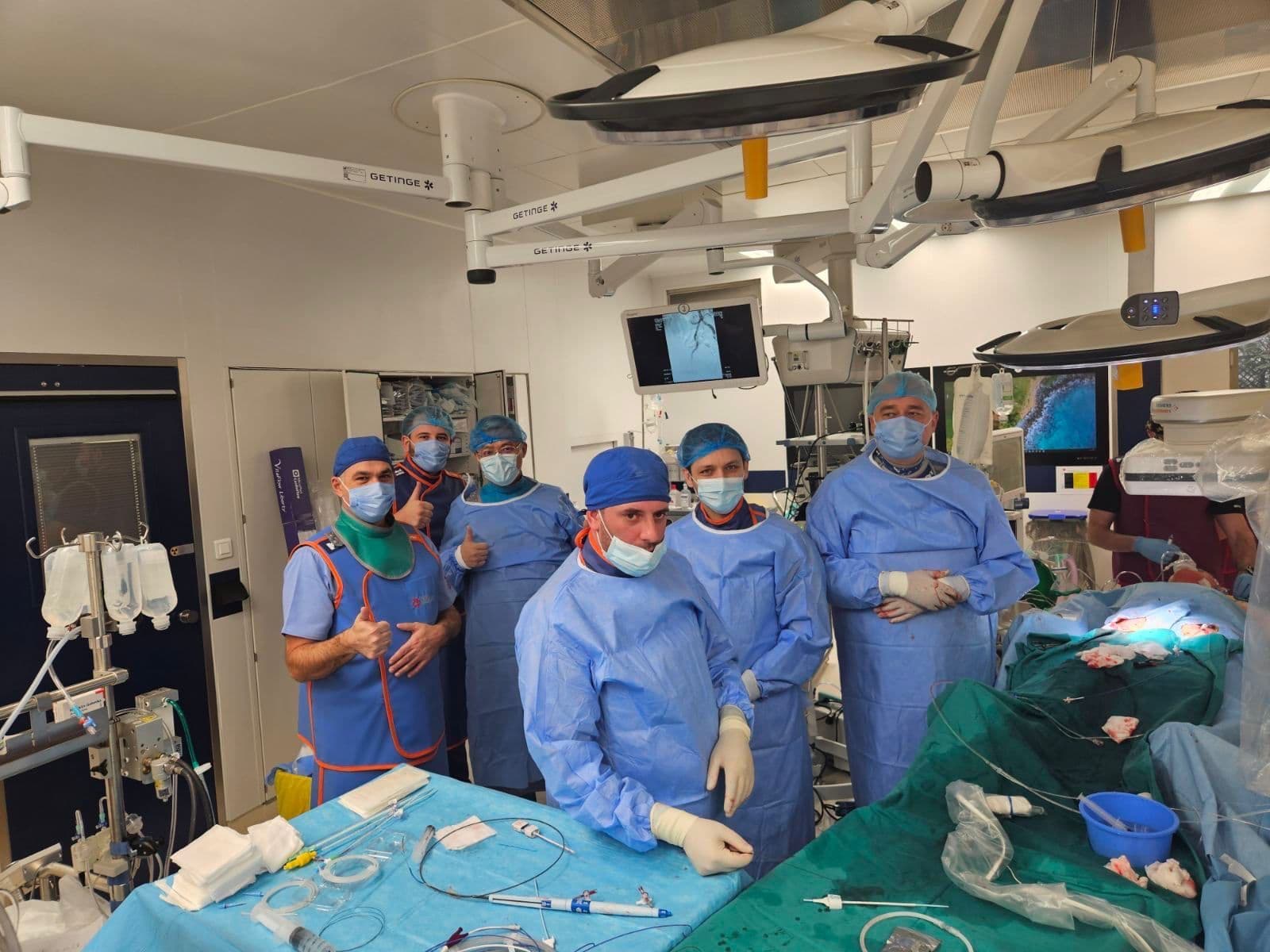 The surgical team in blue gowns and lead aprons in the operating room, some giving a thumbs up
